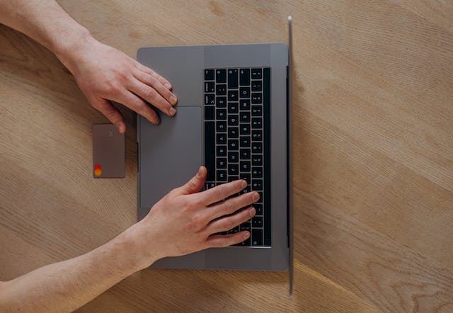 person holding a credit card while on their laptop.